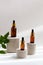 Set of brown glass dropper bottles with a pipette on concrete podiums, green leaves