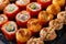 Set of California rolls with fish caviar, baked rolls with cheese and sesame on a dark background