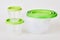 Set of circle transparent plastic food storage containers with green lids isolated
