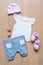 set of clothes and items for the child on a wooden background of T-shirts, pants, socks and pacifiers
