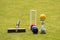 A set of colored balls, a hammer and a winners prize at the croquet wicket on the green lawn
