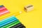 Set of colored pencils and a sharpener on a bright yellow background