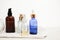 Set of colorful glass bottles with skin care products on white background with copy space. Face serums, acids and packages for