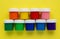 A set of colorful gouache cans isolated on a yellow background. Banks of different colors of gouache paints