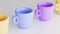 Set of colorful, juicy, matte, empty cups with handle on light background. Cups in yellow, blue and purple. Dinnerware