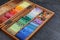 Set of colorful pastels in wooden box on grey stone table, closeup. Drawing materials