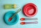 Set of colorful plastic dishware on blue background, flat lay. Serving baby food