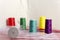 Set of colorful spools of thread, zippers, white fabric and elastic on the pink background