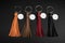 A set of Colorful Tassel key ring on black wooden background. Fashion leather key chain for decoration