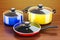 Set of cooking colored kitchen utensils and cookware on the wood