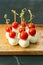 Set of delicious canapes with tomatoes and mozzarella on wooden plate close up