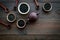 Set of dry tea leaves in bowls and spoons near tea pot for tea ceremony on dark wooden background top view copy space