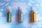 Set of emerald, silver and gold glitters in plastic bottles for soap making on the surface of blue marble, close up, full size,