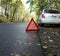 Set emergency stop sign on the road in autumn forest, background white car. concept of roadside and travel assistance