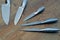 Set of five steel kitchen knifes on wooden table