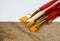 Set of golden bristle paint brushes on white and textured cement background with copy space