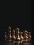 The set of golden chess pieces element, king, queen rook, bishop, knight, pawn standing on chessboard on dark background.