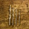 Set of golden drill bits on wooden background