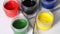 A set of gouache and brushes.  Open cans of paint. Rotate on the subject table. Close-up