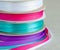 Set of grosgrain ribbons: blue, violet, crimson, white. Background burlap.