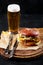 Set of hamburger beer and french fries. A standard set of drinks and food in the pub, beer and snacks. Dark background