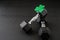 Set of hex head dumbbells with a green glitter shamrock on a black gym floor, happy St. Patrick’s Day