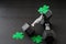 Set of hex head dumbbells with green glitter shamrocks on a black gym floor, happy St. Patrick’s Day