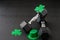 Set of hex head dumbbells with green glitter shamrocks and leprechaun hat on a black gym floor, happy St. Patrick’s Day