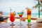 Set of iced cocktails: layered with lime, orange, blue and red cocktail on beach