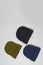 Set of khaki, dark blue and black hipster beanie hats laid out isolated over gray background