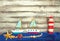 set of kids handcrafted boats, fish, nautical attributes and more on rough vintage wooden background top view