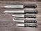 Set of kitchen knives on wood work surface. Filtered image.