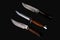 Set of knifes made of Damascus steel with a wooden handle on a isolated dark background