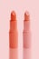 Set of matte lipstick on a delicate pink background, red, raspberry, pink, coral, peach color, close-up, the concept of decorative