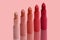 Set of matte lipstick on a delicate pink background, red, raspberry, pink, coral, peach color, close-up, the concept of decorative