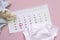 Set of newborn accessories in anticipation of  child - calendar with circled number 23 twenty three, baby clothes, toys on pink