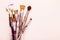 Set of old brushes, flower and palette knife on pale pink background
