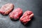 Set of organic alternative cuts beef steaks, top blade, rump and chuck roll, on black textured background, side view with space