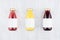 Set of organic fruits juices - orange juice, strawberry, currant in glass bottles with blank label on white wood, mock up.