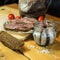 A set of pickled anchovies, in a glass jar. Fresh tomatoes and anchovy fillets on a wooden table. A jar of pickled anchovies.