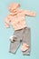 Set of pink children`s clothes on a blue background. Twist with a hood, gray pants, socks and an elephant`s toy.