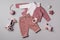 Set of pink clothes and accessories fot newborn girl. Toys, bodysuit, jeans, knitted cardigan on grey backgroundd. Mock