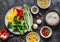 Set of products for vegetarian lunches - pasta, rice, bulgur and fresh vegetables on a dark background, top view