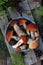 Set of red cap boletus in bowl on wooden background. Brown wild mushrooms. Edible fungus Leccinum Aurantiacum collected in forest