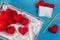 Set of red heart made from velvet fabric lay in white box with notebook and white satin on vintage blue table wood.