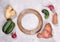 Set of ripe ugly vegetables and round wooden frame on grey concrete background.