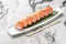 Set of rolls philadelphia kappa with microgreens and green bamboo leaf in a white ceramic plate with chopstick on a bright