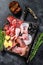 Set of smoked and dried meat Ham, jerky, salted meat, jamon and herbs. Black background. Top view