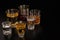 A set of strong alcoholic beverages in glasses, in the presence of whiskey, vodka, rum, brandy, tequila, on a dark background