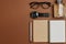 Set of stylish male accessories with a pen, perfume, clock, notepad and glasses on brown background. Minimal concept Fathers Day